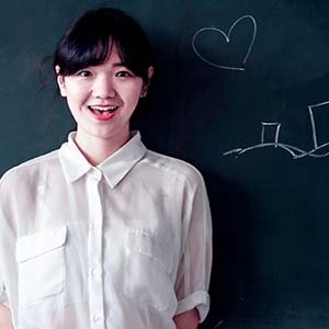 woman smiling in front of chalk board