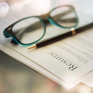 close up of resume, a pencil and a pair of glasses