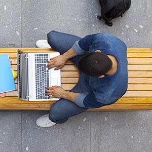 student on bench using laptop